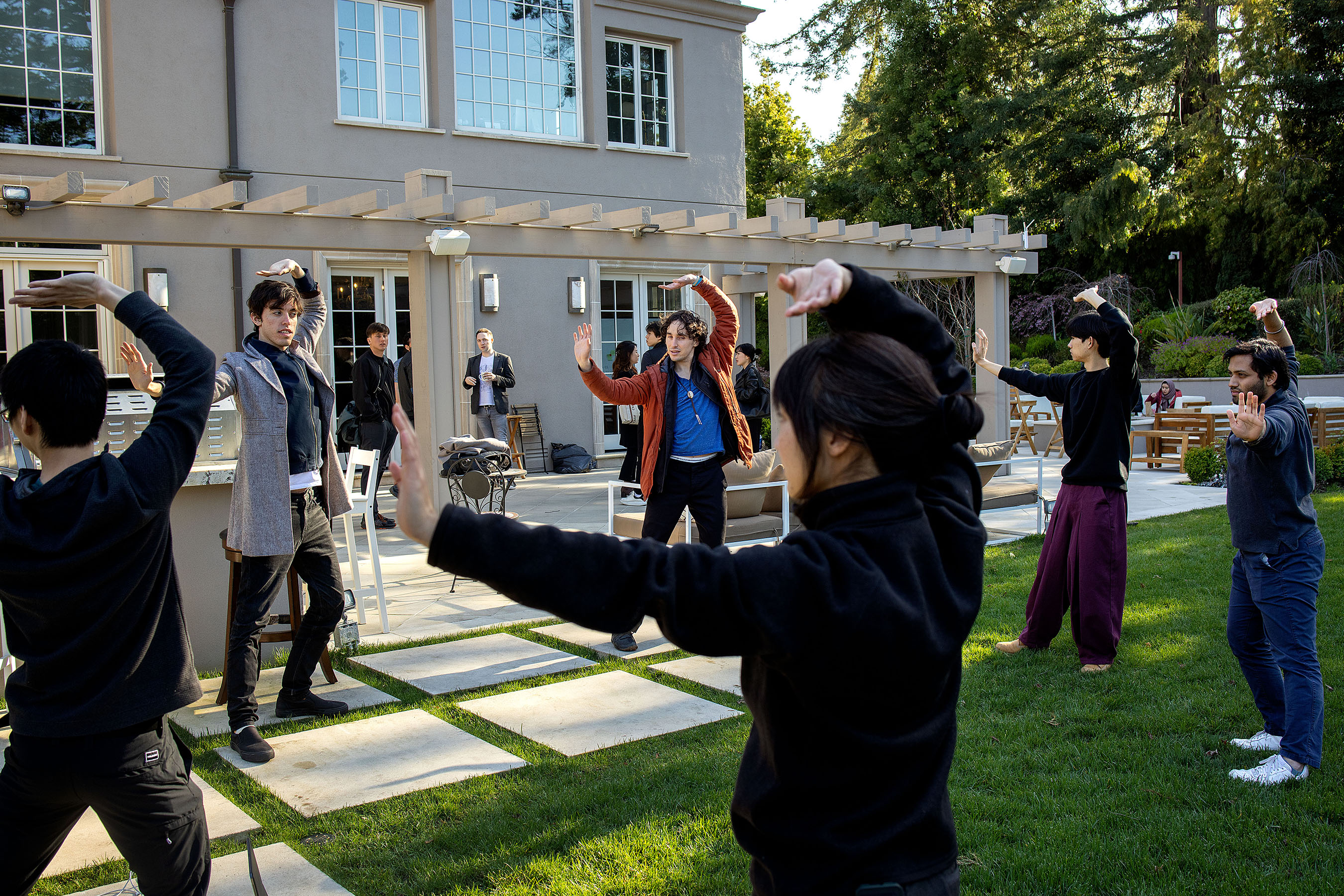 EXTRA: Hackathons are big networking opportunities, with participants frequently meeting people who go on to become co-founders, teammates, friends, even romantic partners. // Jacob Cole (center) leads a Qigong session in the backyard as a break for people competing in the hackathon during the AGI House LLM Hackathon at the “AGI House,” a hacker house in Hillsborough, California on March 25, 2023. The one-day hackathon was planned around the release of GPT-4 and drew hundreds of excited attendees. Hackathons are an opportunity for individuals to build something in a set amount of time, testing and refining their skills, but they are also social events. While coding away, people make friends and build community with one another. 